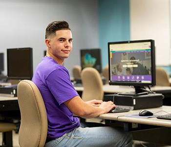 穿着紫色衬衫的人，坐在电脑前.